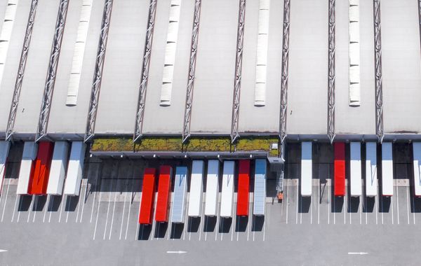 Draufsicht einer Logistikimmobilie mit Fokus auf Laderampen vor der weiße und rote Container stehen