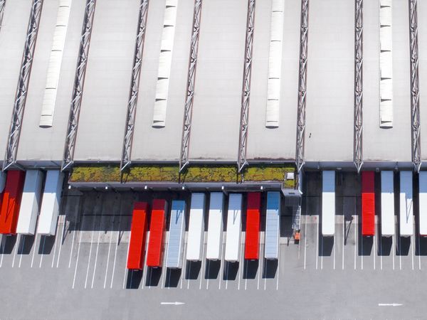 Draufsicht einer Logistikimmobilie mit Fokus auf Laderampen vor der weiße und rote Container stehen